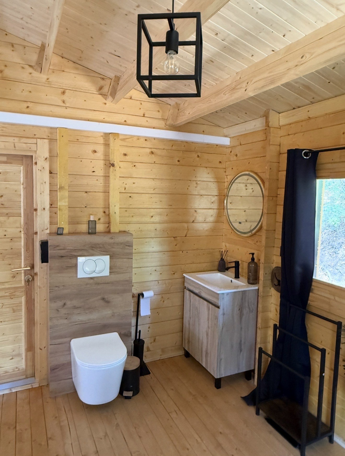 Salle d'eau avec WC suspendu et meuble vasque dans un chalet en bois du Domaine des Parcs