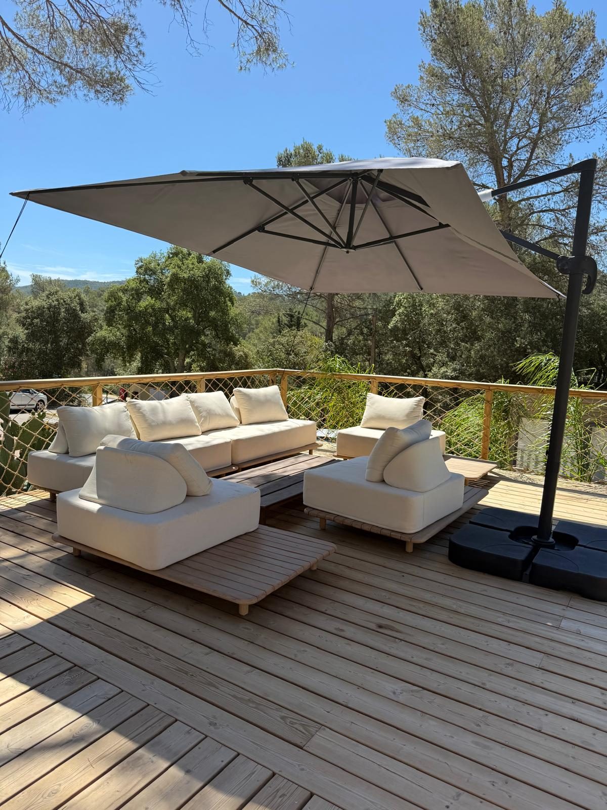 Salon d'extérieur sous grand parasol face à la nature