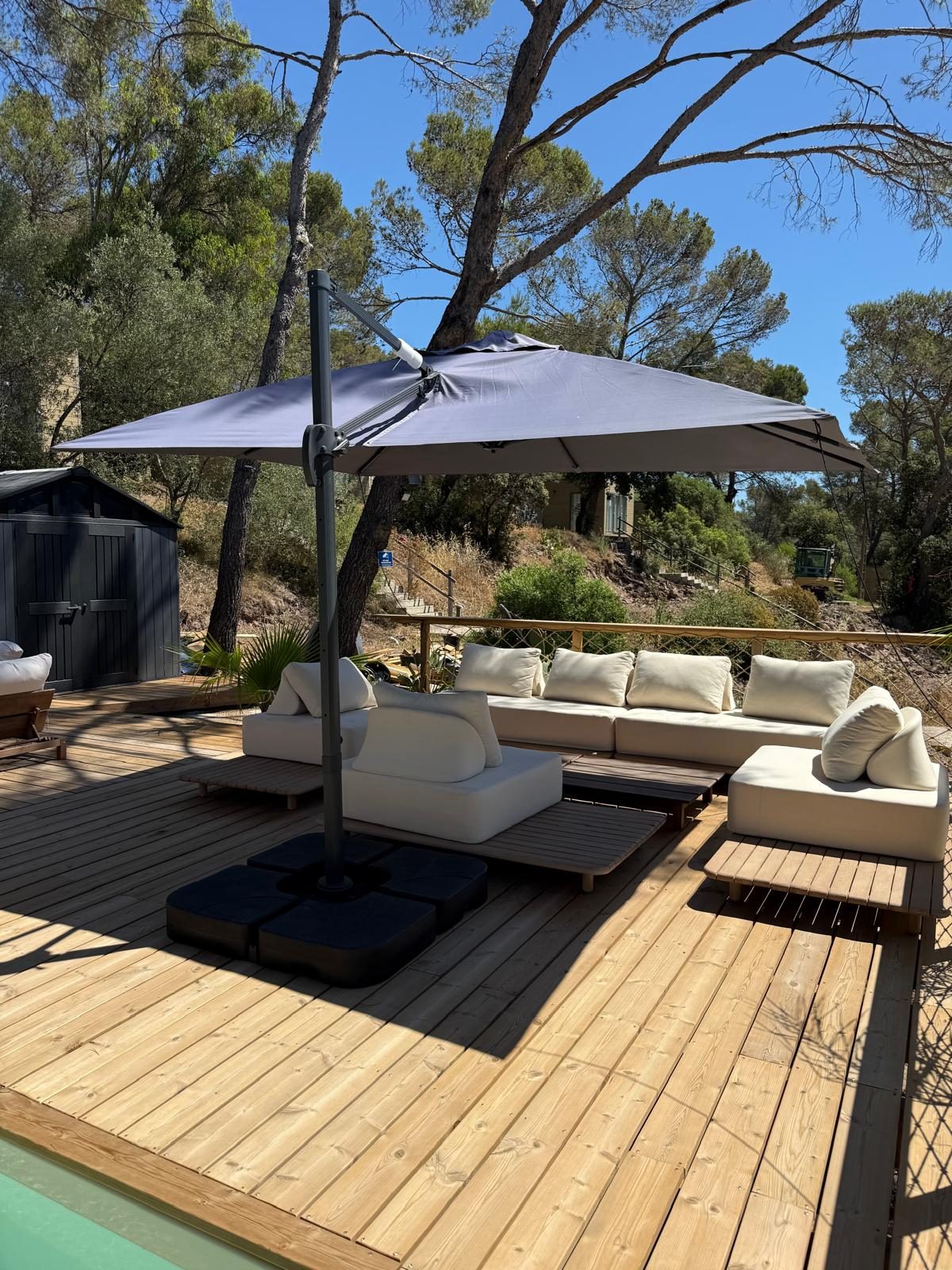 Salon d'extérieur sur la terrasse d'un chalet, entouré de pins