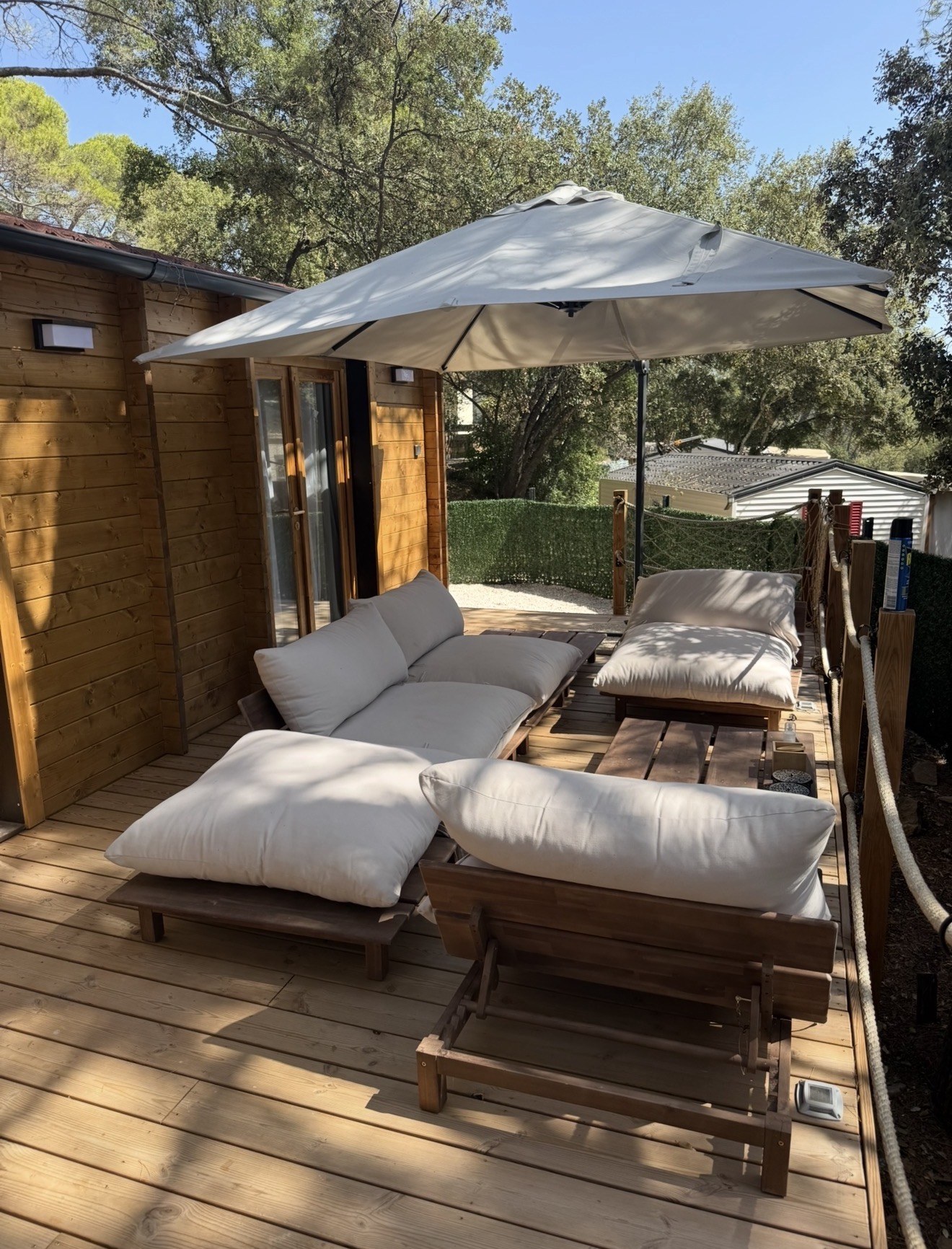 Transats sous parasol sur la terrasse d'un chalet en bois du Domaine des Parcs