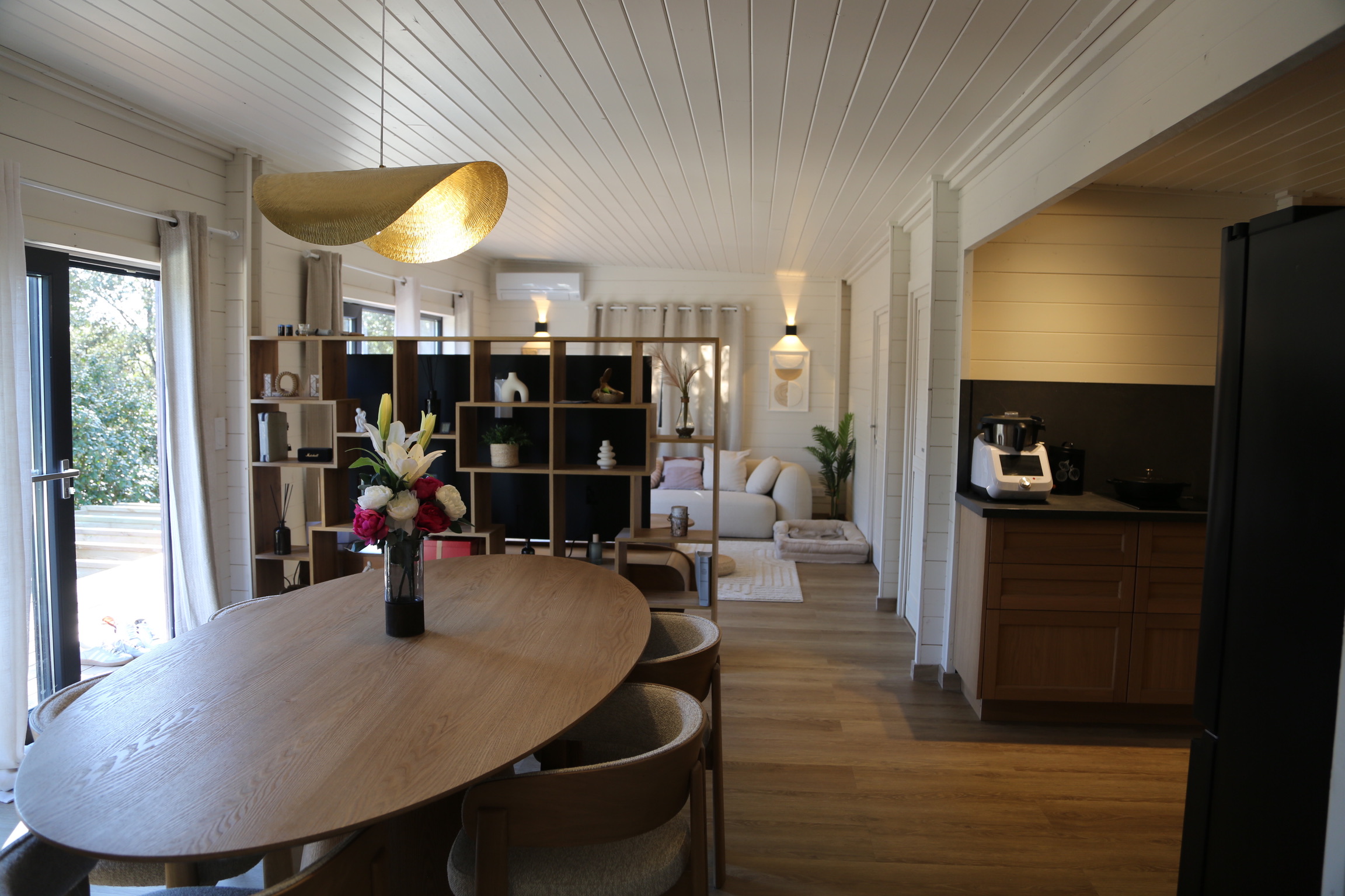 Salon intérieur haut de gamme d'un hébergement du domaine, bibliothèque murale et cuisine noire mate