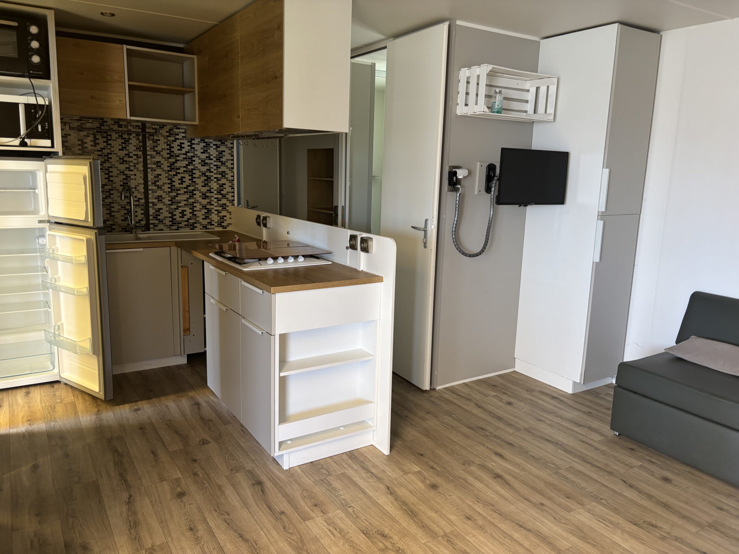 Cuisine ouverte d'un mobil-home du domaine, meuble blanc et îlot central