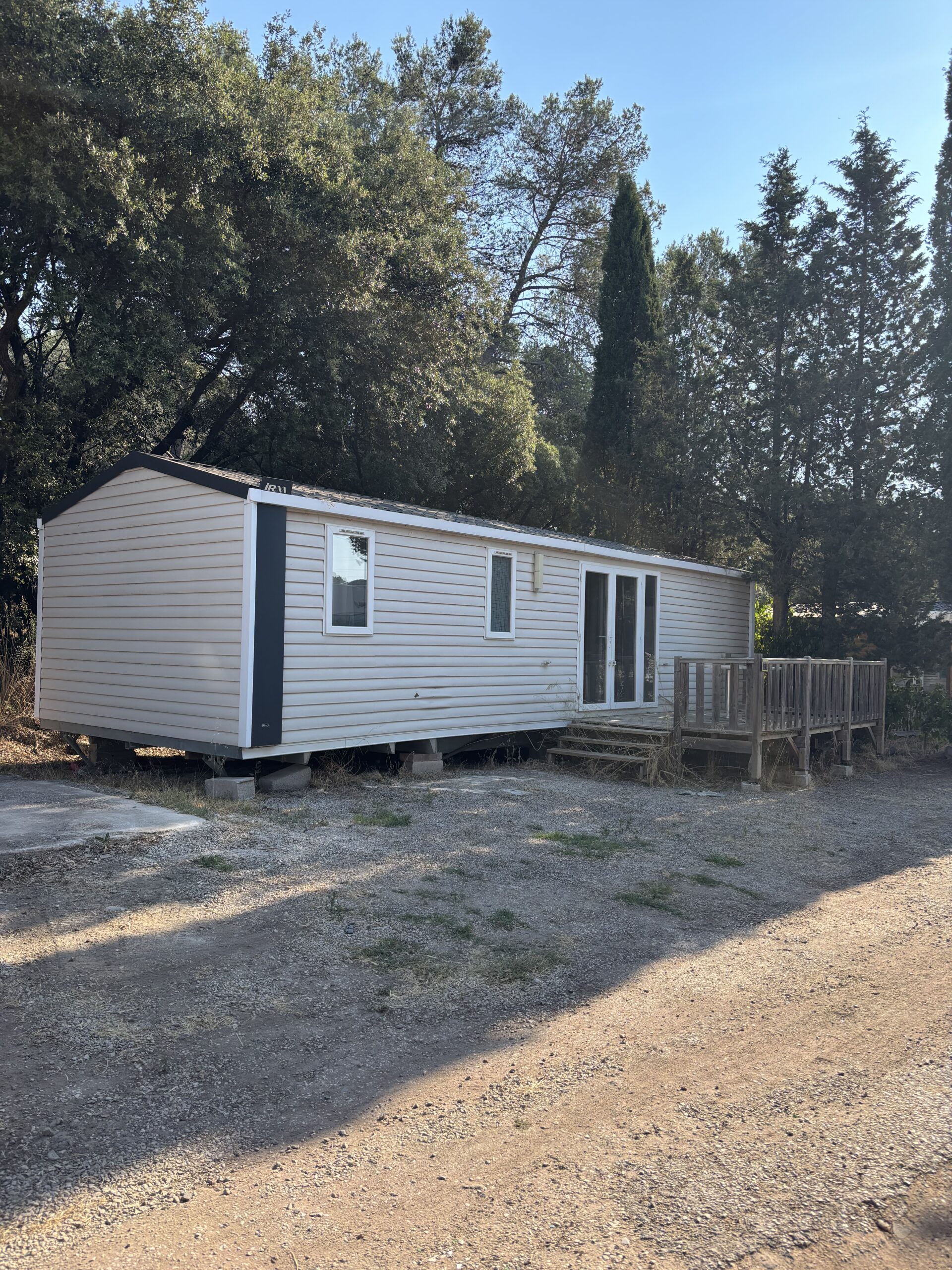 Mobil-home blanc du domaine avec terrasse en bois surélevée