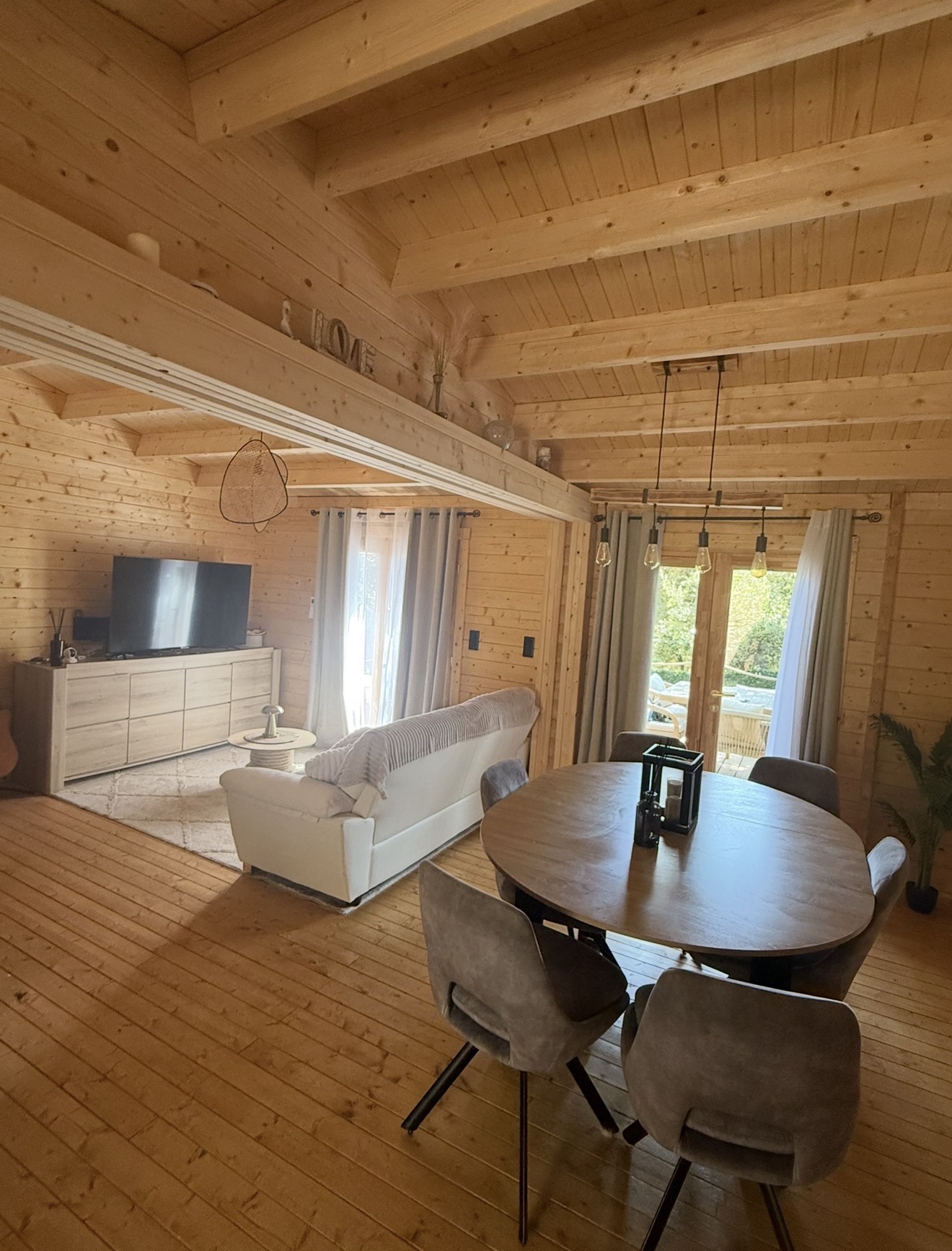 Salon et salle à manger en bois d'un chalet du domaine, canapé blanc et table ronde
