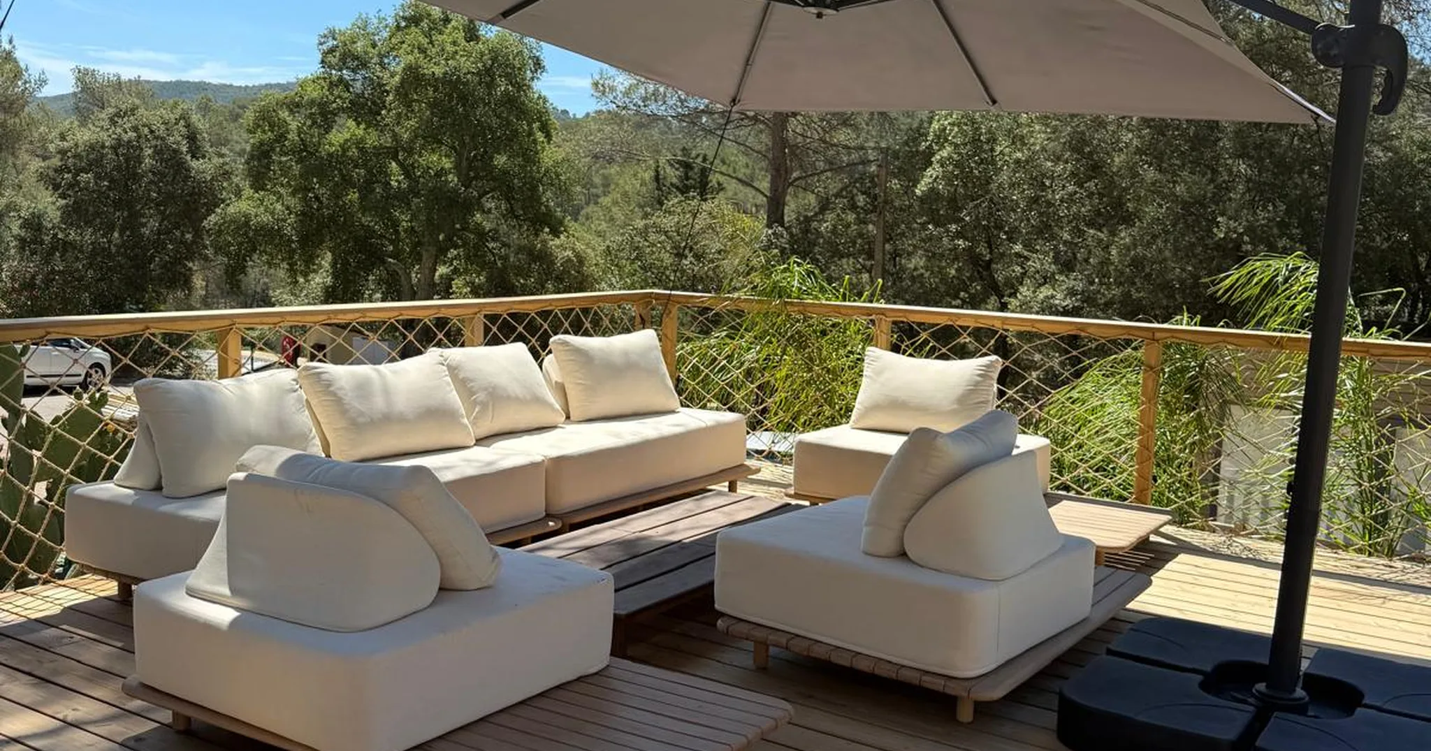 Salon extérieur sur une terrasse en bois, face à la pinède du domaine